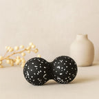 Balle de massage dos noire et blanche présentée avec objets décoratifs zen