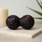 Balle de massage dos noire à motifs roses dans une ambiance minimaliste beige