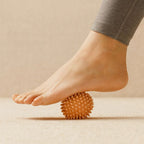 Balle de massage picots utilisée sous un pied pour détendre la voûte plantaire et soulager les tensions musculaires