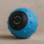 Balle de massage vibrante bleue posée sur une surface sable