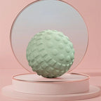 Boule de massage verte posée devant un miroir dans une ambiance zen