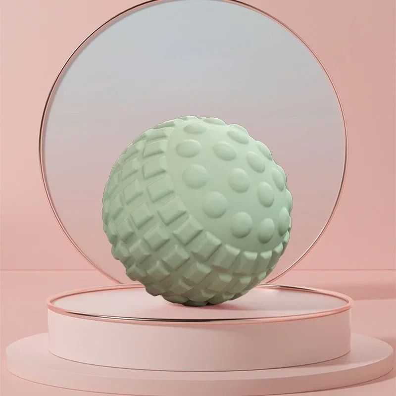 Boule de massage verte posée devant un miroir dans une ambiance zen