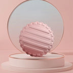 Boule de massage rose exposée sur support rose en fond neutre