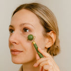 Jeune femme massant son visage avec un rouleau de jade boule pour stimuler la peau