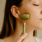 Jeune femme massant son visage avec un rouleau de jade à picots pour stimuler la peau