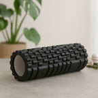 Rouleau de massage musculaire noir posé dans un environnement relaxant