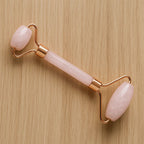 Rouleau facial en quartz rose à plat sur fond bois, outil de soin beauté naturel