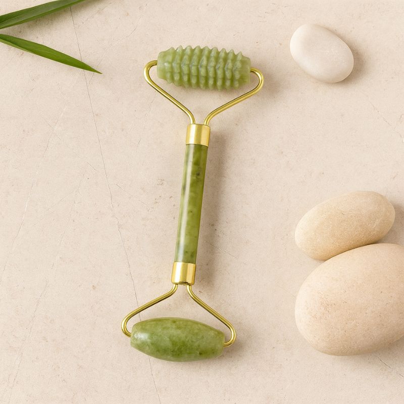 Rouleau visage en pierre de jade avec embout texturé, posé sur fond naturel