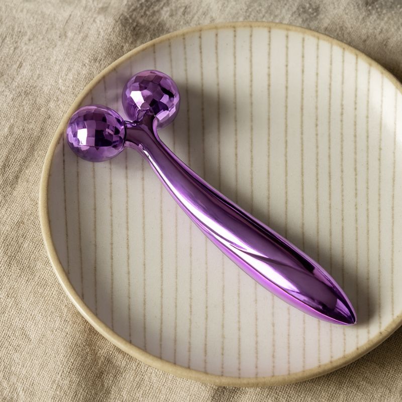 Roll on visage violet posé sur une assiette rayée dans un décor zen